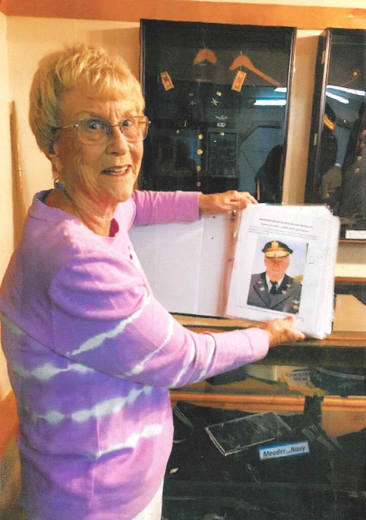 Elna Meader showing album of Lt. Col. Jerry Meader's military career at Town of Horicon Museum